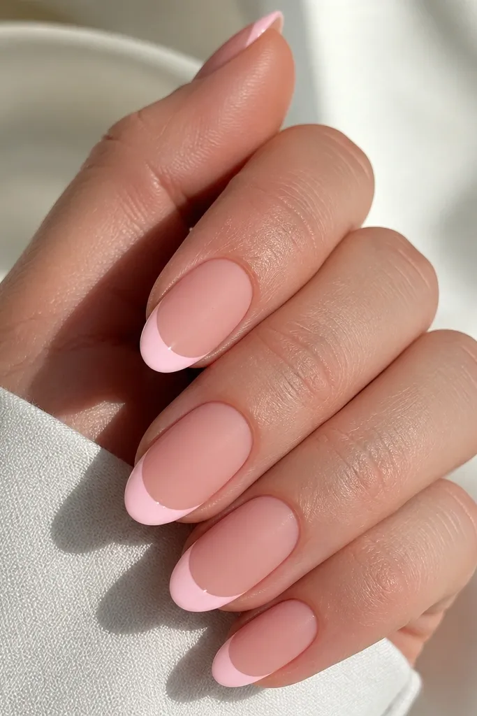 Matte soft pink nails with glossy french tips. The contrast makes the tip curve look sharply defined.