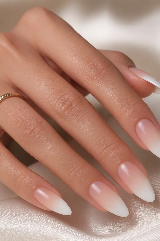 Almond nails where the tip starts bright white and fades into a creamy white gradient before meeting a sheer pink base. The fade looks smooth, not streaky.