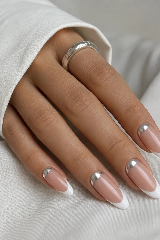 Almond nails with a bright white French tip. A silver foil half-moon sits near the cuticle, centered and slightly curved.