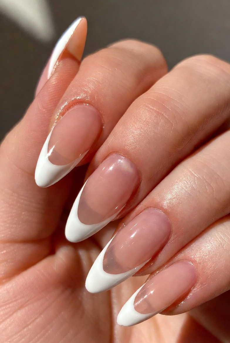 Five nails shown in a close-up. The base is sheer nude. Only a thin, curved white line sits at the free edge like a small smile. The lines are centered and the arc is narrow, leaving the sides mostly nude.