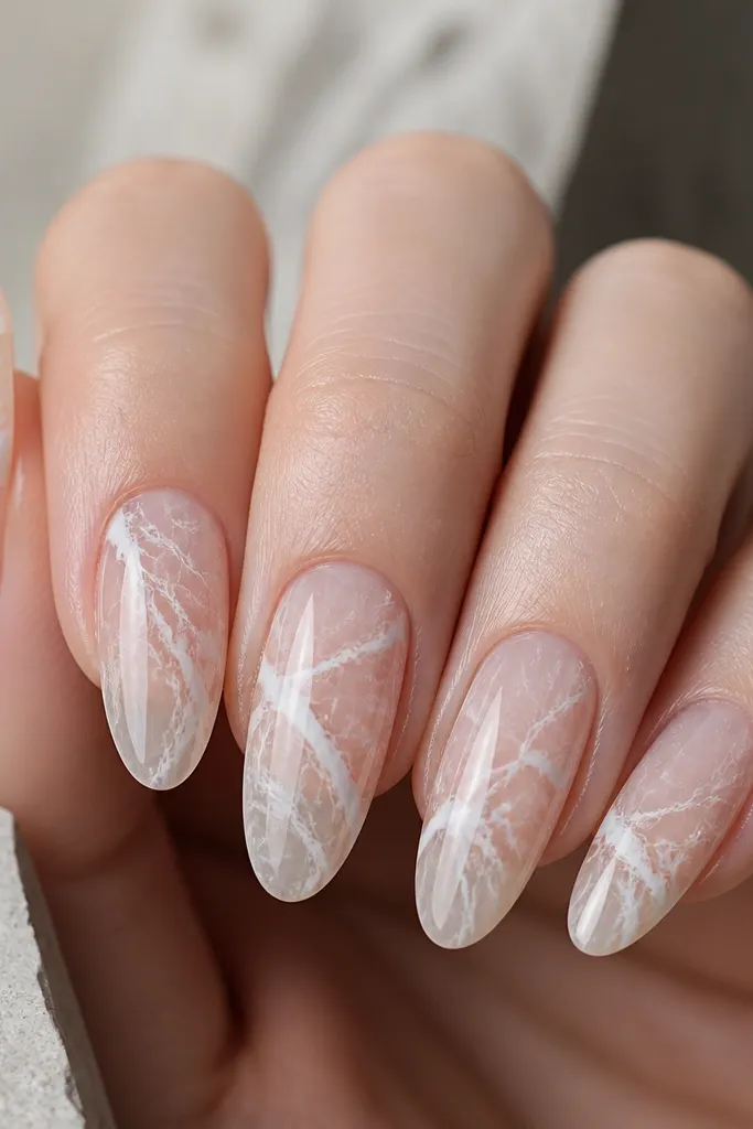 Five nails. The base is clear glossy. Thin white and off-white veins branch from the center and taper out toward the sides. The veins look like real marble, not painted lines.