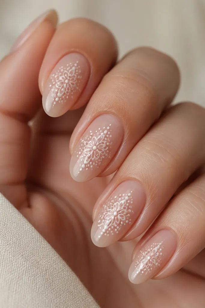 Four nails show a sheer base. From the center, white dots and tiny lace-like loops fade outward toward the sides. The pattern stays concentrated in the middle and doesn't cover the edges.