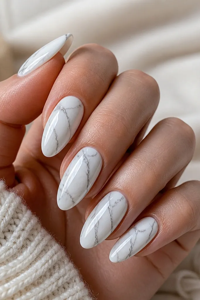 White almond nails with soft marble swirls. Thin charcoal-gray veins run through the milky white, with a glossy finish.