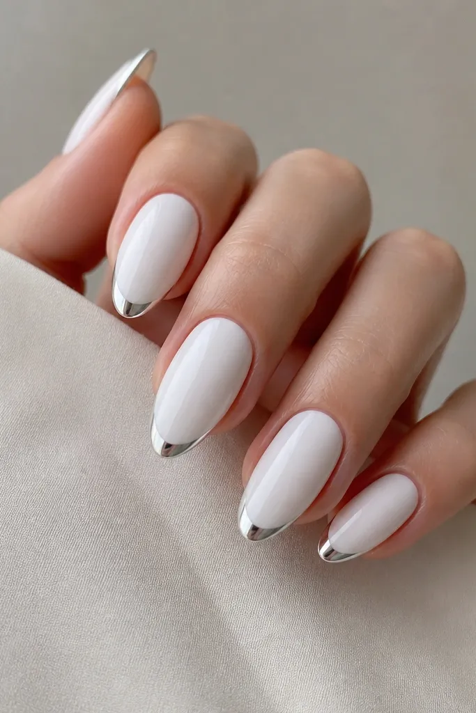 Almond nails with a thin chrome French line at the tip, mostly opaque white nail beds, mirror snow-white tips.