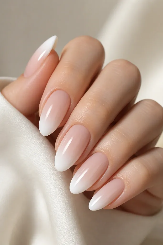 Almond nails where the tip is white but fades into a sheer nude toward the middle. The outer edge still has a clean curve, and the finish is glossy.