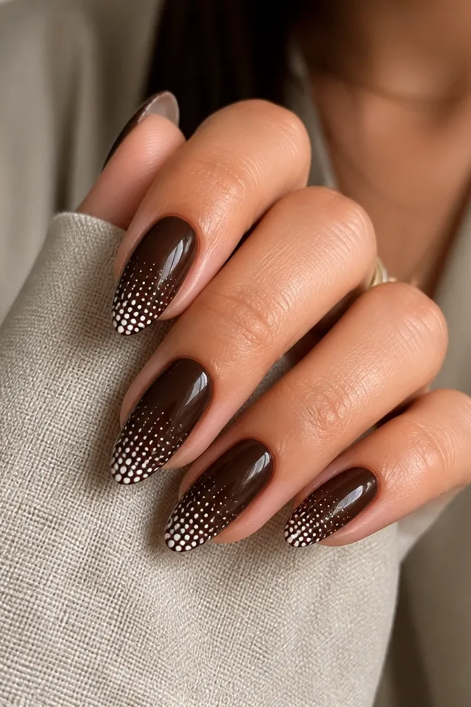 Almond nails with a glossy espresso brown base and thin white halftone dots only on the tips, forming a gradient from small dots to larger dots. Clean cuticles.